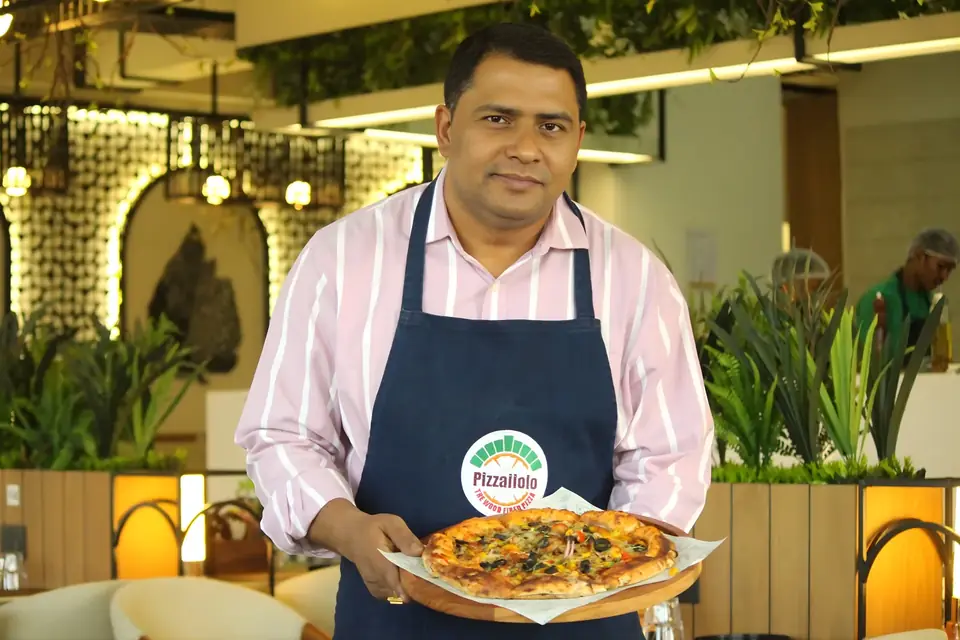 Pizzaiiolo chef presenting a wood-fired pizza